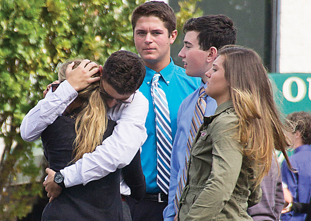 Friends embrace outside the funeral, where more than a thousand attendees paid their respects to Tom Cutinella. (Credit: Paul Squire, file)