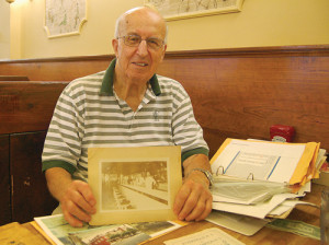 Tony Meras holds up a picture of family members working in the diner decades ago. (Credit: Nicole Smith)