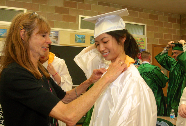 Mercy teacher Patricia Doroski helps Suren Gu of Southampton with her gown. (Credit: Barbaraellen Koch)