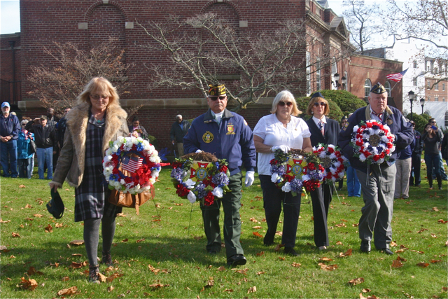 Placing the wreaths representing Fleet Reserve Linda Chase (from left), Commander VFW Post 2476 Richard Friscia, VFW Ladies Auxiliary president Dorothy Minnick, American Legion 273 Ladies Auxiliary vice present Darlene Folkes, and American Legion 273 past commander Larry Judd. (Credit: Barbaraellen Koch)