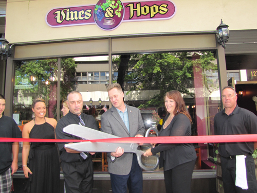 TIM GANNON PHOTO | Riverhead Supervisor Sean Walter is flanked by Jeff and Christine McKay is celebrating the opening of their new venture, Vines & Hops, in downtown Riverhead Sunday. 