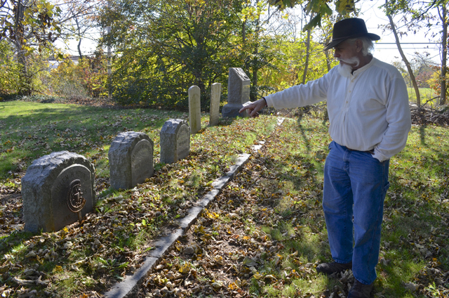 Bill Meyer points out dates on gravestones in the church’s cemetery.