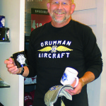 Ted Kole poses with the merchandise he designs and sells to commemorate the corporation.