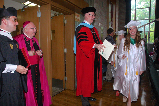 McGann-Mercy campus minister Matt Prochilo (left), Bishop William Murphy (center) and Principal Carl Semmler stood by as the graduates proceeded through the auditorium before the commencement ceremony Wednesday afternoon. (Credit: Barbaraellen Koch)