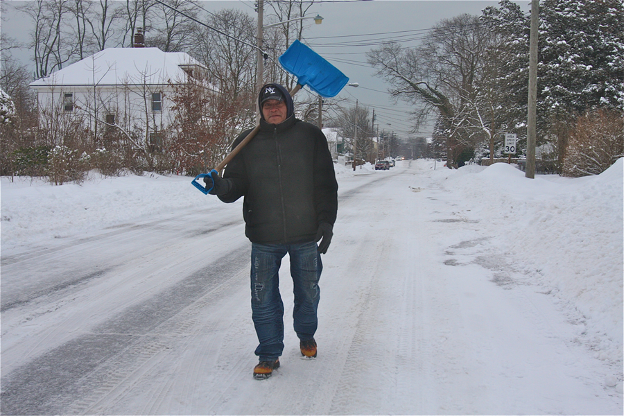 Santos Aguilar walks along Sweezy Avenue Monday morning in Riverhead to look for shoveling work. (Credit: Barbaraellen Koch)