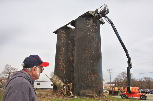 Lloyd Corwin, 80, watches as his grandson Blake gingerly tears down the old Purina feeds storage tower which was built from clay tiles and has deteriorated over the years since it was constructed after World War II next to the Crescent Duck Farm in Aquebogue. (Credit: Barbaraellen Koch)